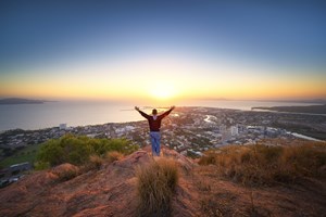 A man with outstretched arms posed against the sunset on a hilltop on the iconic Magnetic Island. Fly direct from Toowoomba to Townsville (and return) on Airnorth | www.wellcamp.com.au