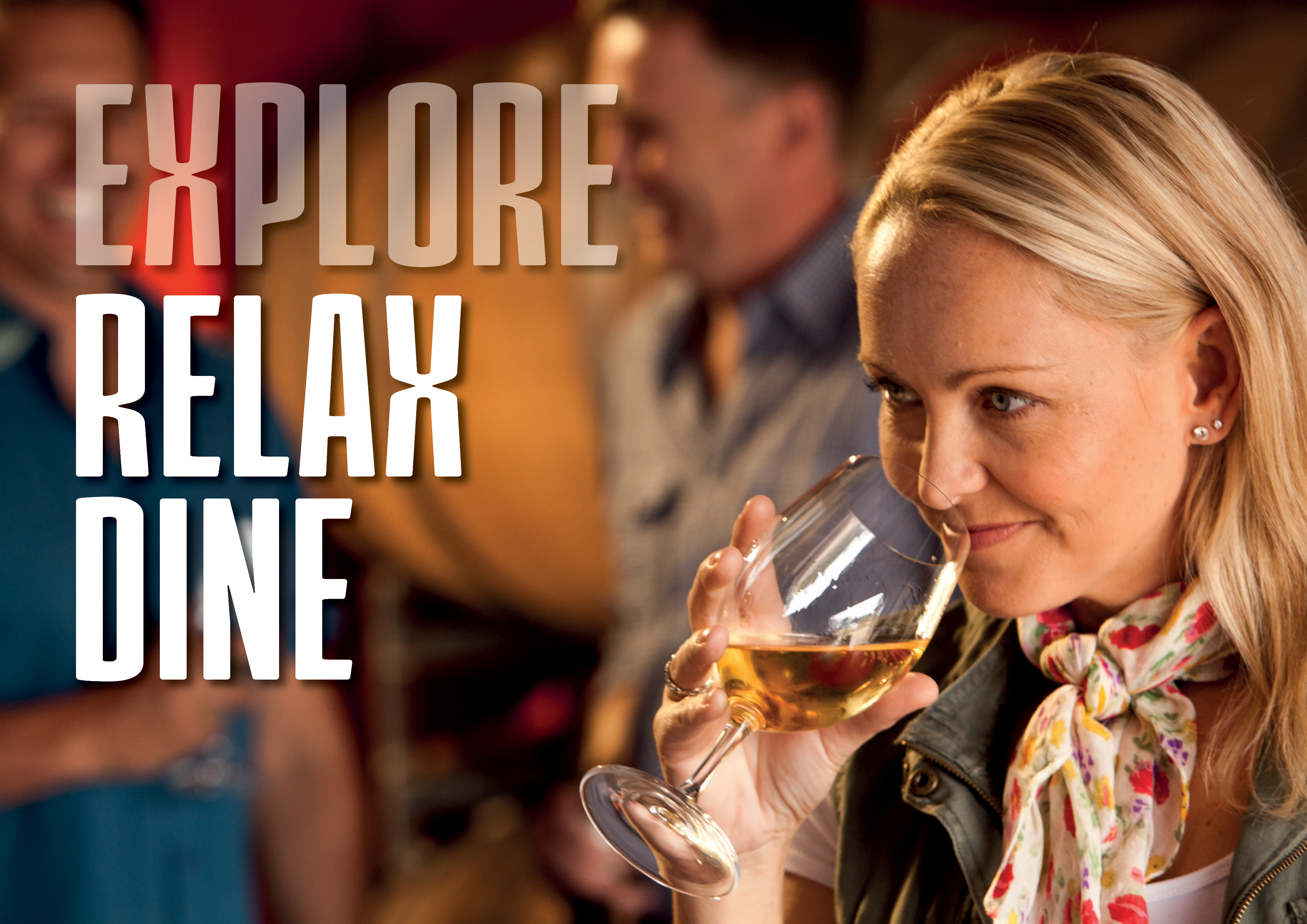 A lady with long blonde hair and a floral scarf around her neck sniffs a white wine at a wine tasting session in the Granite Belt. www.wellcamp.com.au